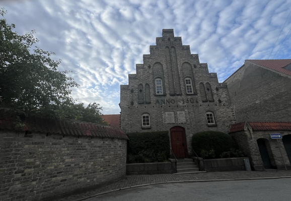 Aalborg Kloster på en baggrund af bølgeskyer der ligger helt tæt om gavlfacaden