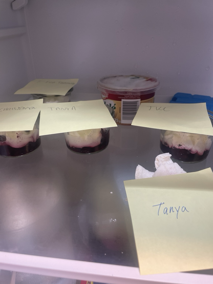 Køleskabshylde med fire små skåle pavlova med gule post-its med navnene Tanya, TKC og Christensen