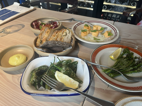 Flere deleretter på et bord (bl.a. stegte padrones, broccolini, citrusmarineret kuller med melon og rigtig godt brød)
