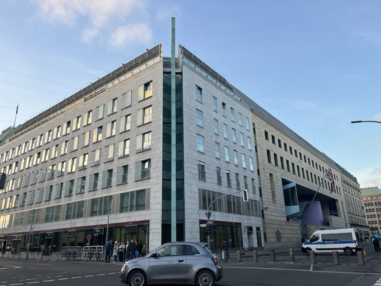 Høj lejlighedsbygning i hvid marmor hvor hjørnesektionen er åben men markeret af en høj kobberplade