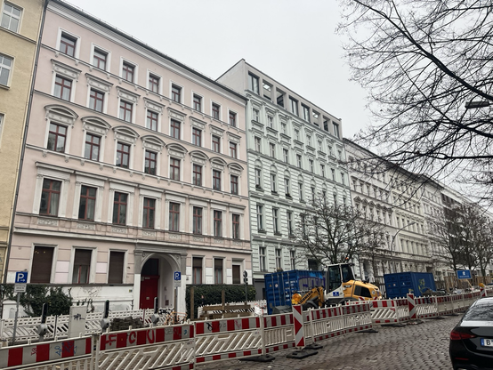 Flere lejlighedsblokke hen ad en vej, malet i forskellige pastelfarver (lysegul, lyserød, lys mint, sand)