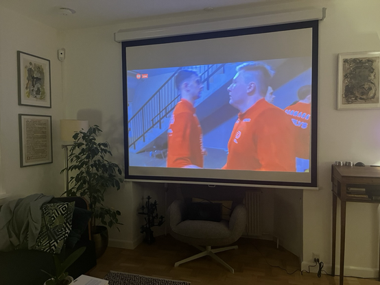 Stue med stort lærred sat op foran karnappen. Billedet viser opstart til håndboldfinale i EM 2026