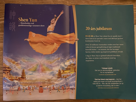 Opslag i folder om dansetruppen Shen Yun. Godt halvdelen af siden viser et billede af en kvindelig danser i orange kjole der flagrer om hendes ben som er spredt i et spring. Bag og under hende er et tegnet himmelrige med kinesiske bygninger, skyer, en engel med lysstråler i pastelfarver og nederst en masse dansere. Overskrifterne i teksten er Shen Yun - skønheden ved guddommelige væseners dans og 20-års jubilæum 