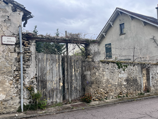 Murværk og trælåge foran en formentlig forladt grund i en lille fransk by. Begge dele er meget slidt af vind og vejr men ser pittoresk ud