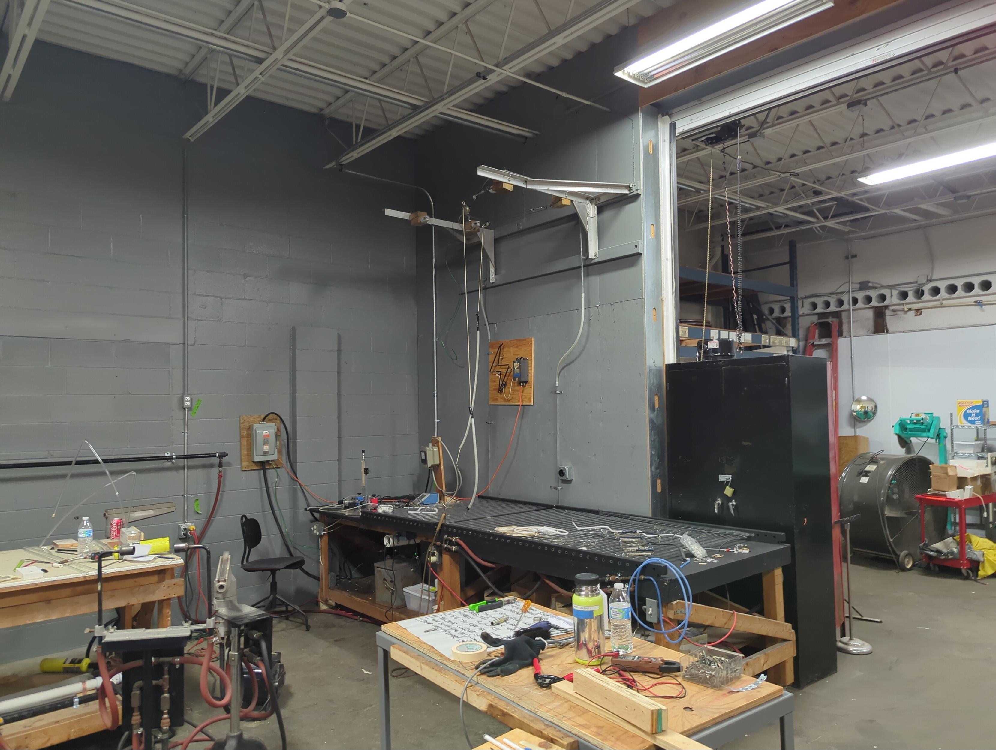 zoomed out view of the shop with the most popular cannon crossfire torch and a ribbon burner in the frame along with a messy catchall table (keeping bending areas clear) and the bombarder trolly setup.